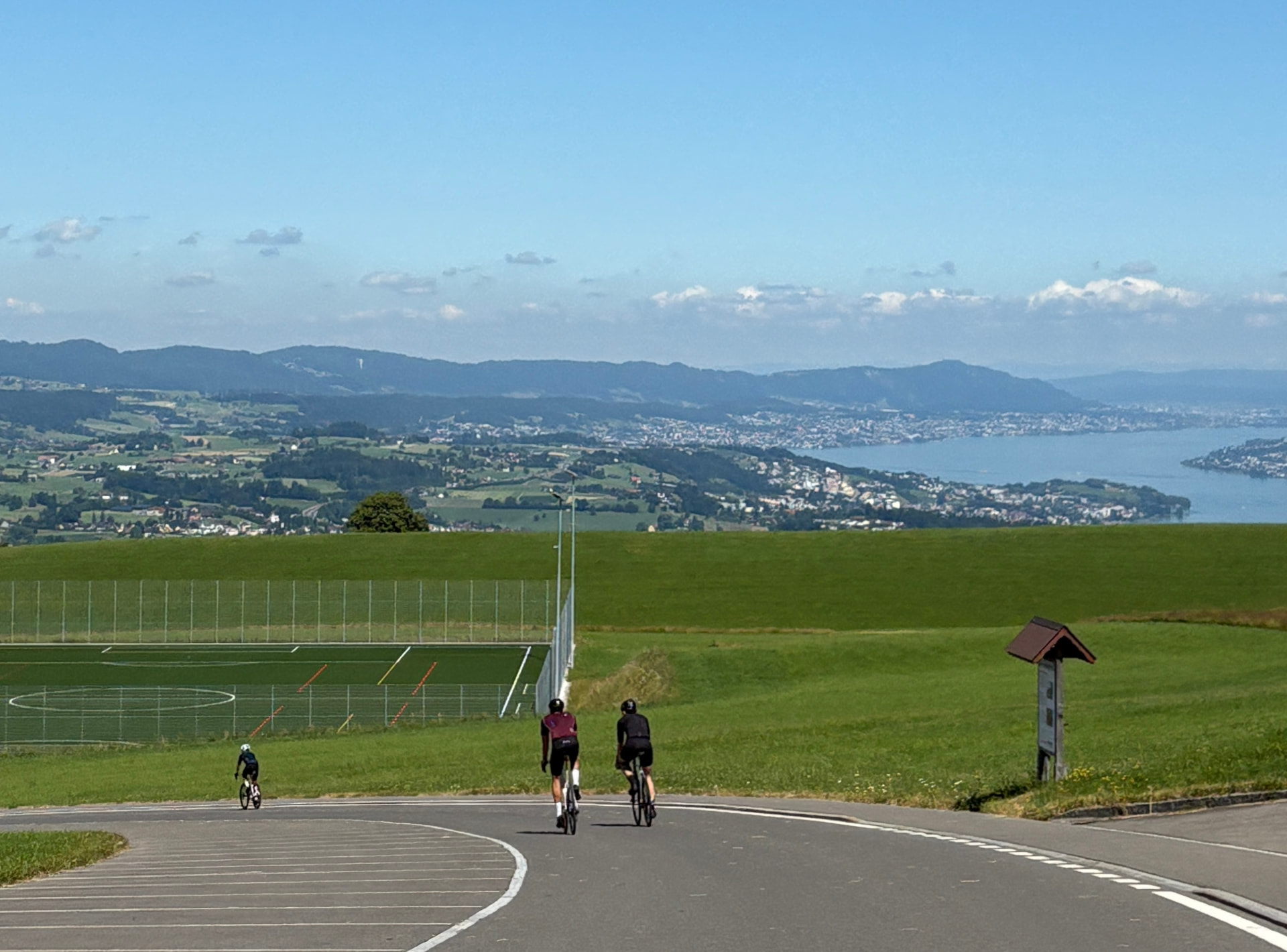 Cyclists riding above Lake Zurich with the Zurichsee and Alps in the distance
